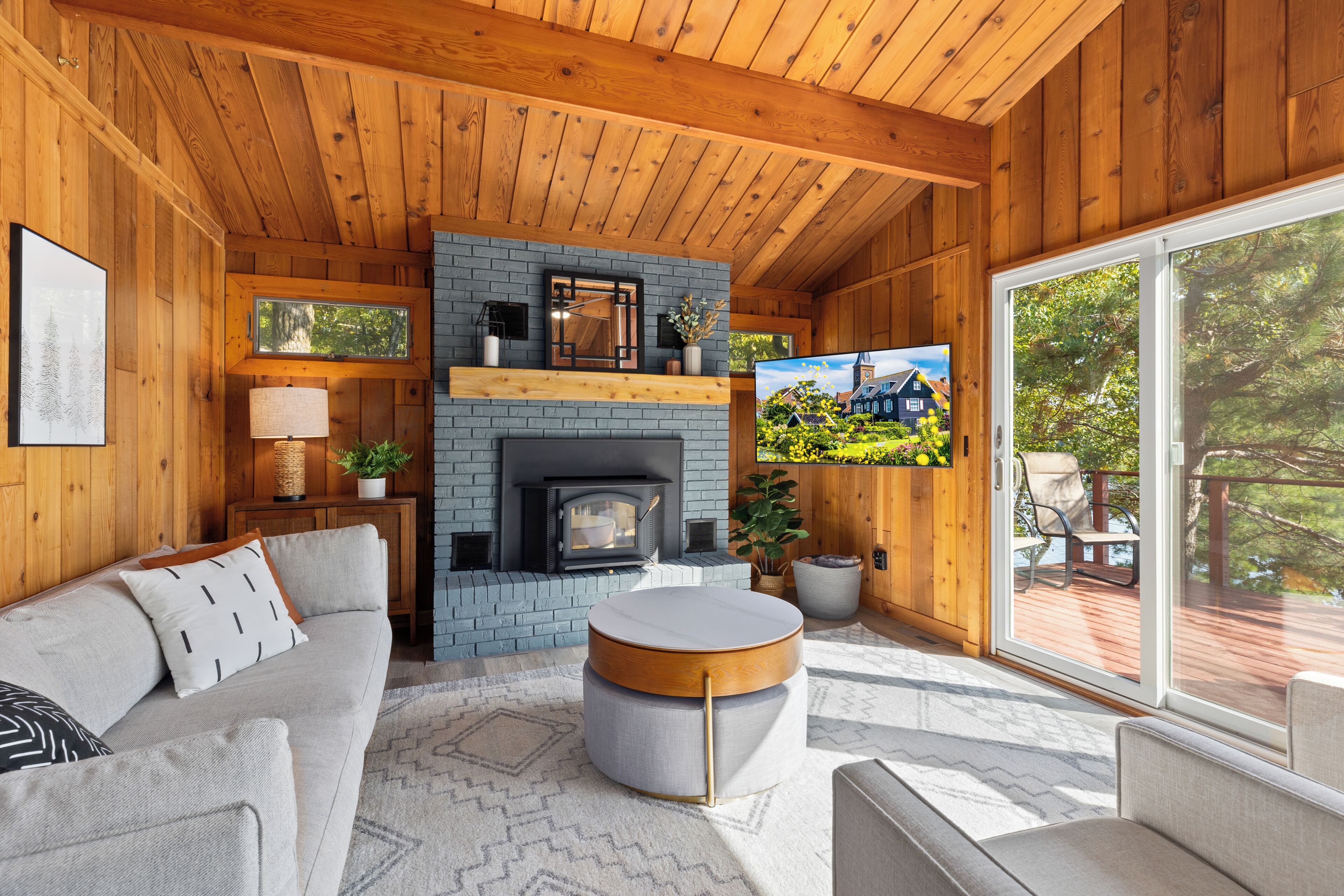 A cozy living room with a fireplace, wooden walls, a sofa, and a television.