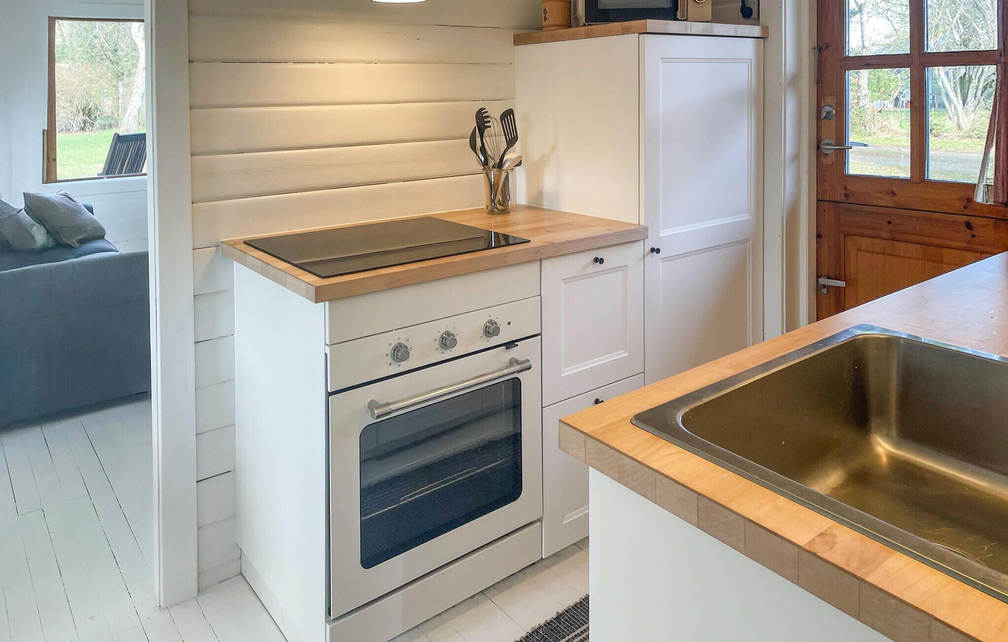A compact kitchen with a built-in oven, a sink, and a wooden countertop.