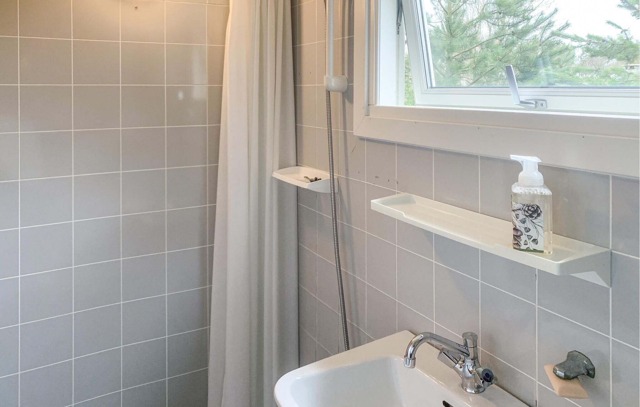 Une salle de bain avec une douche, un lavabo et une fenêtre.
