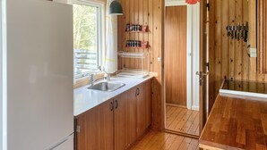 Une cuisine de taille réduite, avec des meubles en bois, un réfrigérateur blanc, un évier et une fenêtre.