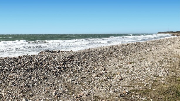 Une plage rocheuse où les vagues se brisent sur le rivage.