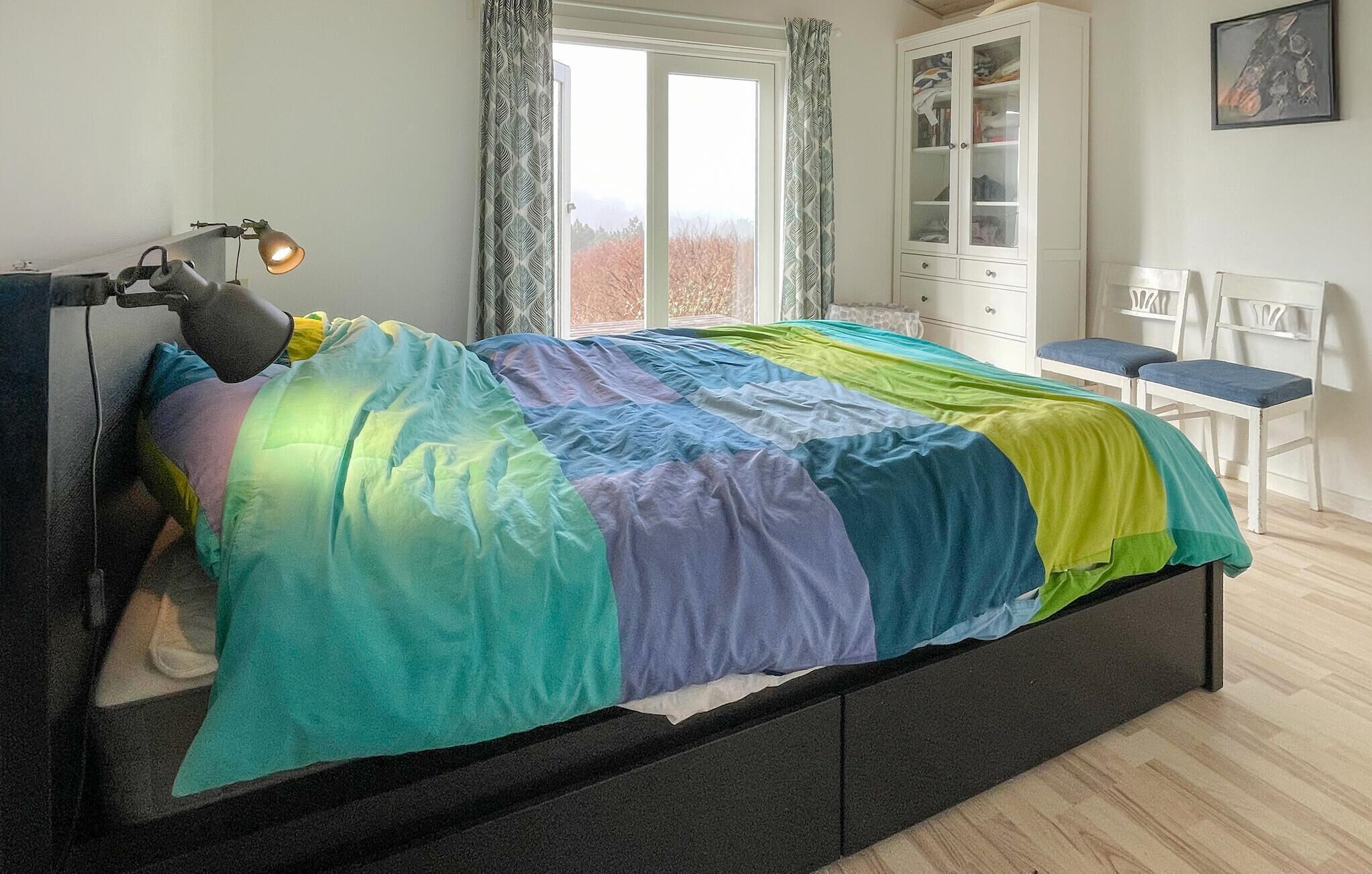 A bedroom with a bed, a desk, a chair, a cabinet, and a window.