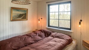 Et værelse med en seng, et vindue, et billede og væglamper.