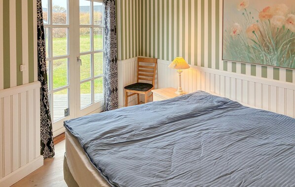 A room with a bed, a chair, a table, and a lamp.