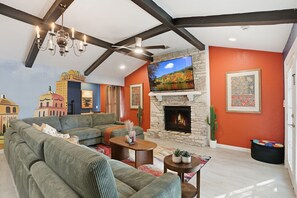 Una sala de estar con chimenea de piedra, televisión y un ventanal grande.