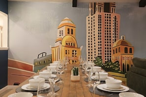 A dining table set with white plates, bowls, and wine glasses, centered with a cactus plant. - Epic Family Getaway : Pool, Arcade, & Mini Golf (San Antonio)