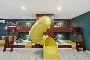 Quarto com beliche e um escorrega amarelo.
