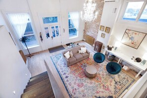 Ein geräumiger Wohnbereich mit Sofa, Sesseln, einem gemusterten Teppich und einer Treppe zu einer weiteren Ebene.