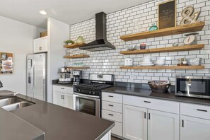 Una cocina moderna con armarios blancos, un refrigerador de acero inoxidable, una estufa a gas y un microondas.