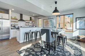 Una cocina moderna con una isla central, taburetes de bar y un ventanal con vistas a la ciudad.