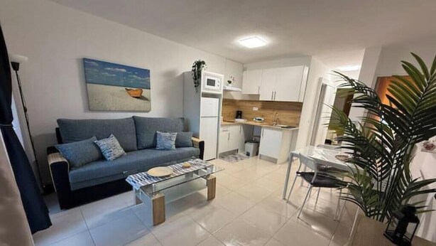 Un salon moderne comprenant un canapé, une table basse et un coin repas avec des chaises et une table.