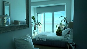 Una camera da letto con un letto, una sedia, una scrivania, uno specchio e vista sull'esterno.