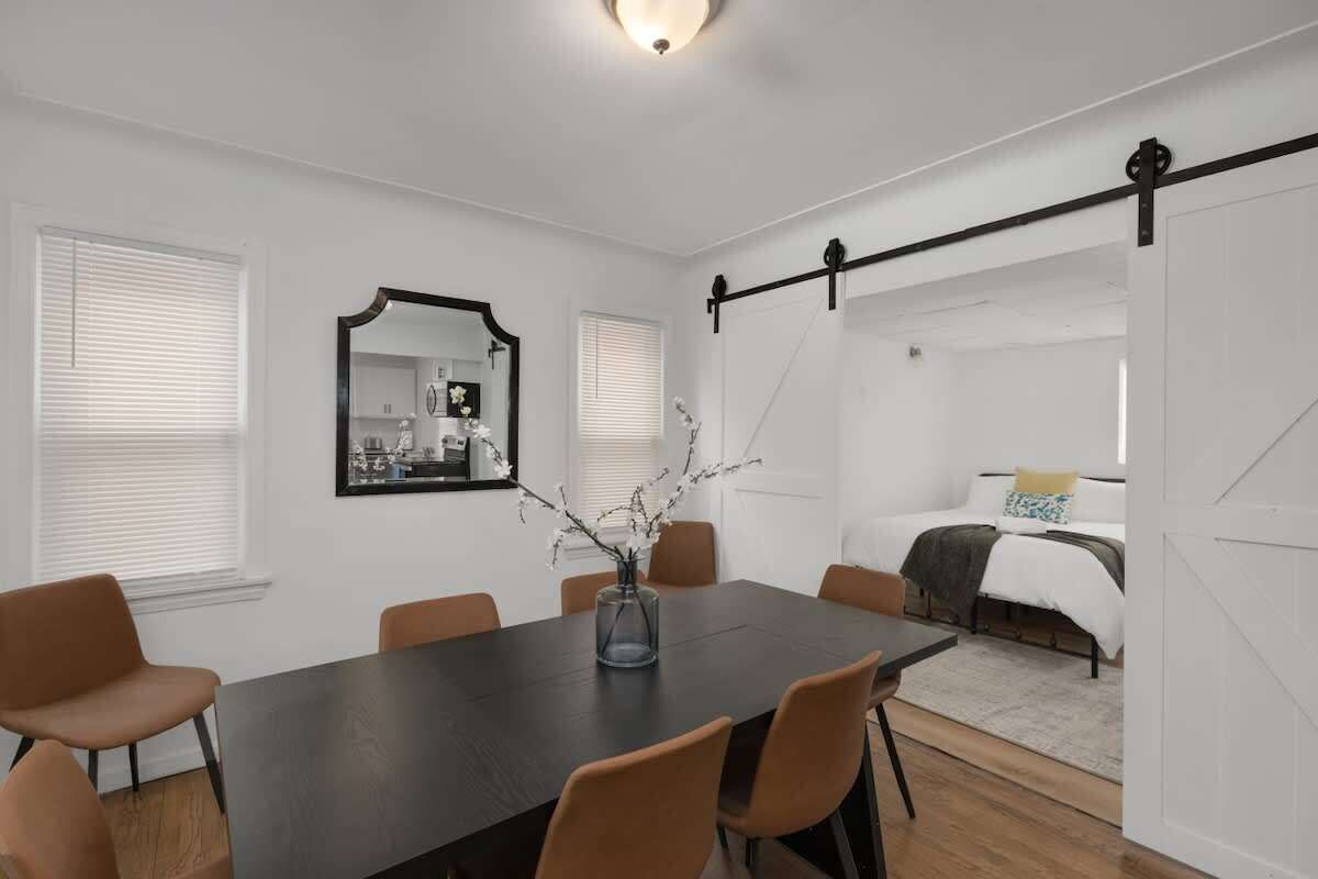 Un dormitorio moderno con cama, mesita de noche y ventana con persianas.