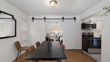 Une cuisine moderne avec une table à manger noire, des placards blancs et un four à micro-ondes suspendu.
