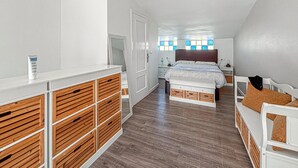 Un dormitorio con una cama, mesitas de noche, un aparador y una ventana con vidrieras.