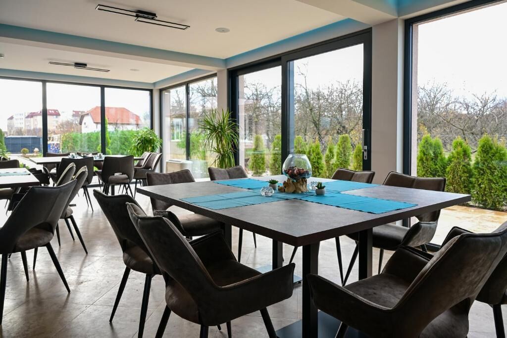Un comedor moderno con ventanas amplias, una mesa central con individuales azules y sillas alrededor.
