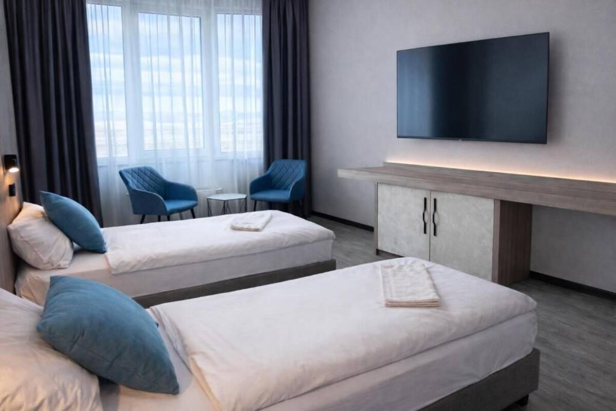 Habitación de hotel con dos camas, televisión, una mesita y una silla.