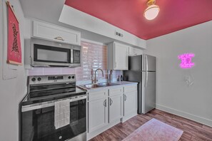 A kitchen with white cabinets, a stainless steel refrigerator, a microwave, and a stove. - Modern 2BR Near Broadway - Free Parking & Fast WiFi (Nashville)