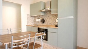 A modern kitchen with a wooden table and chairs, a built-in oven, and a microwave. - Vacation House - A Ridosso dei Sassi (Matera)
