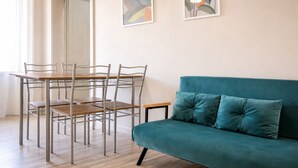 A dining area with a table and chairs, a teal sofa, and abstract wall art. - Vacation House - A Ridosso dei Sassi (Matera)