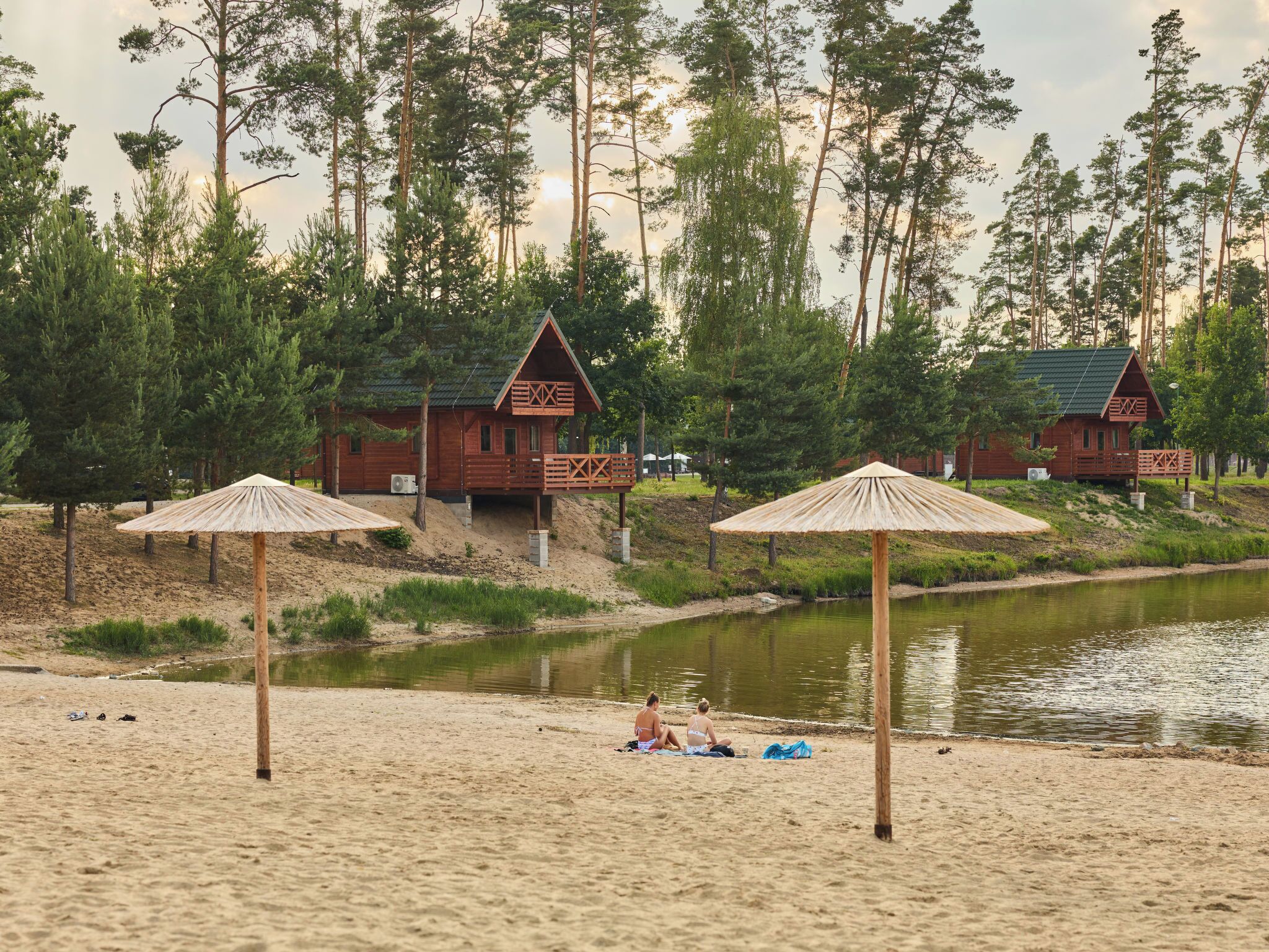 Une plage avec des cabanes en bois et des parasols.
