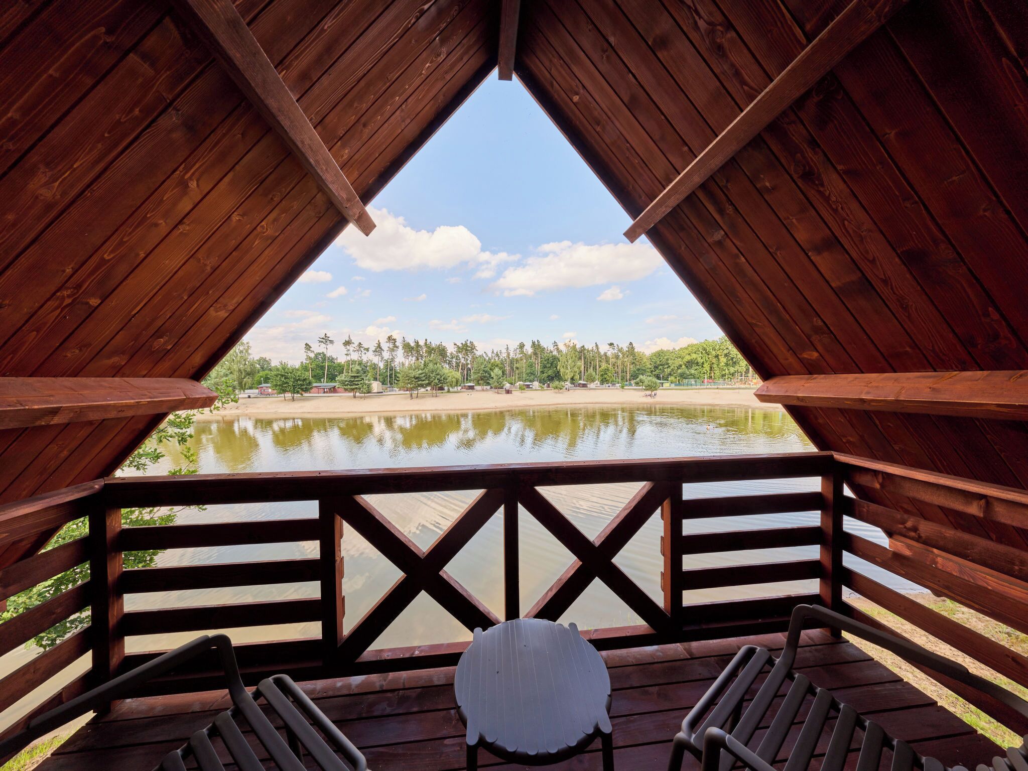 Une terrasse en bois surélevée offrant une vue sur un lac et des arbres.