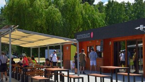 An outdoor seating area with tables and benches, a covered pavilion, and a restaurant building with a sign.