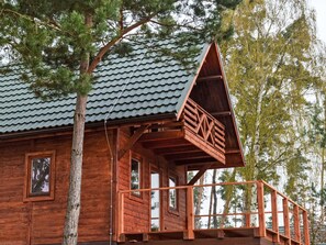 A wooden cabin with a sloped roof, a balcony, and a window.