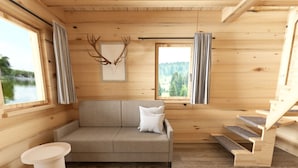 Een houten cabin interieur met een bank, een kleine tafel, een trap en een lijst met een hertengewei aan de muur.