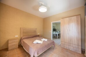 Un dormitorio con cama, mesitas de noche, un armario y un baño visible a través de una puerta abierta.