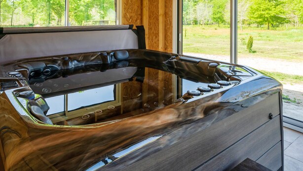 A spa tub with a glass enclosure, wooden walls, and a view of the outdoors. - "Chambre de Laluby" Room with Jacuzzi and Air Conditioning (Arx)
