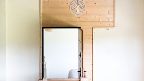 A wooden door with a tree cut-out design, leading to a room with a bed and a hanging light fixture. - "Chambre de Laluby" Room with Jacuzzi and Air Conditioning (Arx)