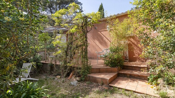 Un jardín con pared de ladrillo, escalones y una silla.