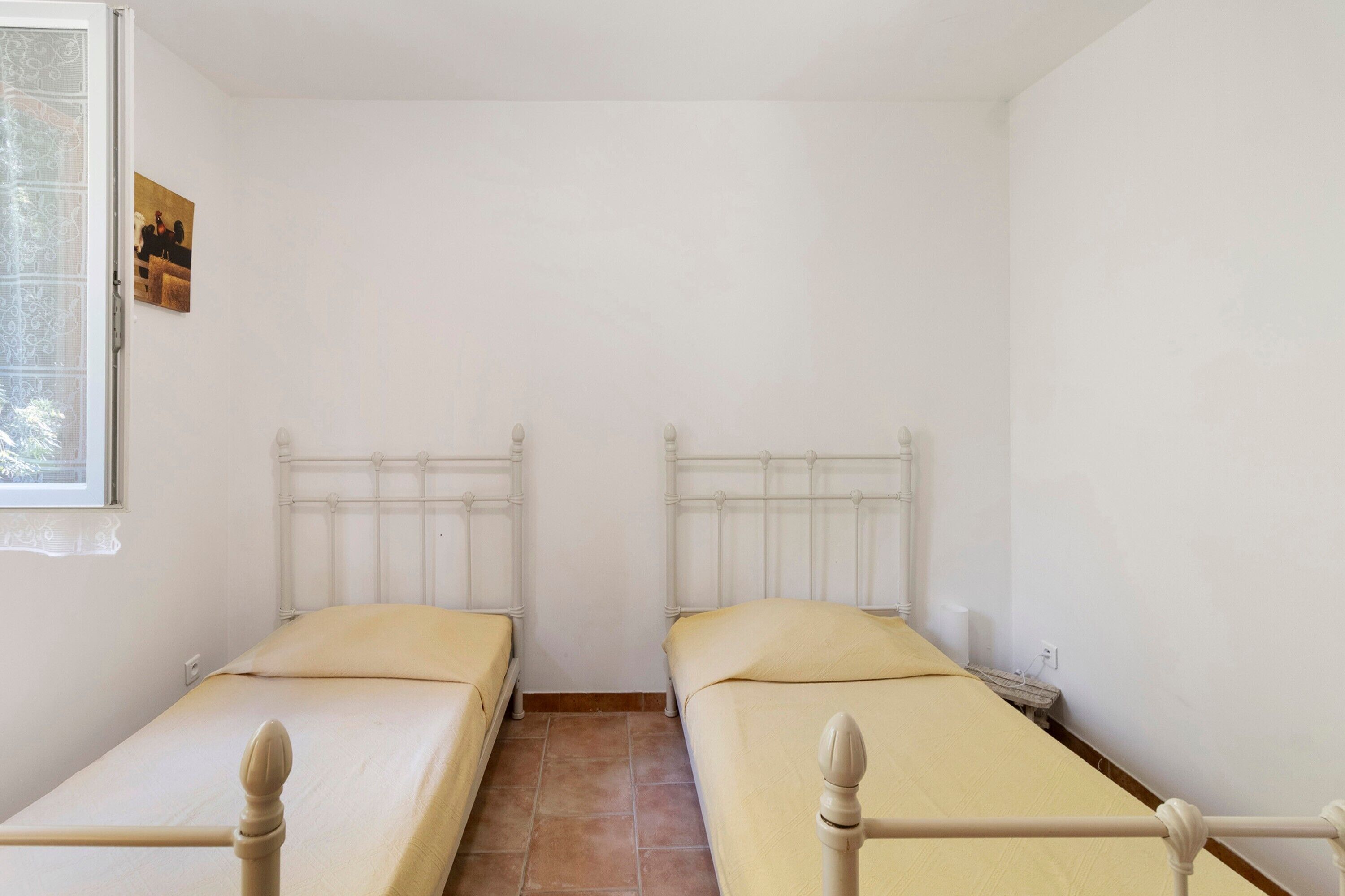 A room with two single beds, a window, and a small table.