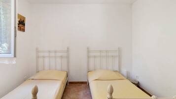 A room with two single beds, a window, and a small table.