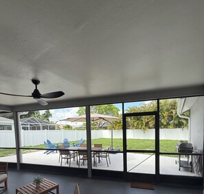 A covered patio with a ceiling fan, large windows, and outdoor seating. - Beautiful 3-bedroom house with AC and Fast Wi-Fi in charming Cape Coral (Cape Coral)