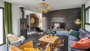 A modern living room with a fireplace, sofa, coffee table, and a television. - Gorgeous home in Dinard with private swimming pool, can be inside or outside (Dinard)
