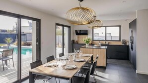 A modern kitchen with a dining area, large windows, and a pool view. - Gorgeous home in Dinard with private swimming pool, can be inside or outside (Dinard)