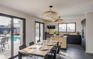 A modern kitchen with a dining area, large windows, and a pool view. - Gorgeous home in Dinard with private swimming pool, can be inside or outside (Dinard)