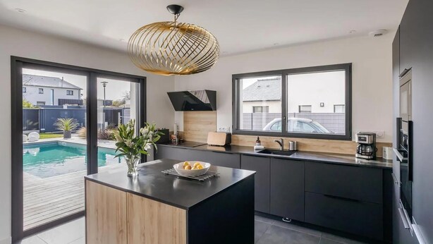 A modern kitchen with a central island, large windows, and a view of a swimming pool. - Gorgeous home in Dinard with private swimming pool, can be inside or outside (Dinard)