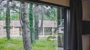 A room with a large window, a flat-screen TV, and a wooden floor. - Hotel La Reposee Rest. L'escu De Runfao (Liffre)