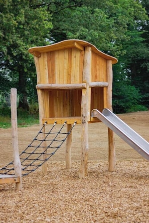 A wooden play structure with a slide and climbing net. - Hotel La Reposee Rest. L'escu De Runfao (Liffre)