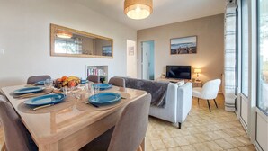 Un coin repas avec une table dressée pour quatre personnes, un téléviseur, un canapé et une grande fenêtre.