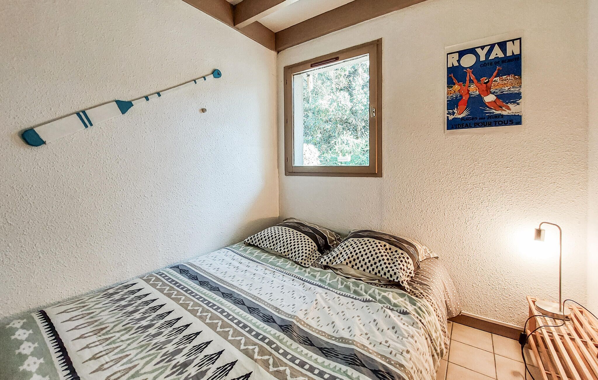 A bedroom with a bed, a window, a poster, and a lamp.