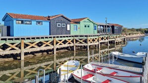 Una fila di edifici in legno colorati, con un molo di legno che si estende in acque calme, dove sono ormeggiate delle imbarcazioni.