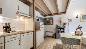 Una cucina con macchina per caffè, forno a microonde e zona pranzo con tavolo e sedie.