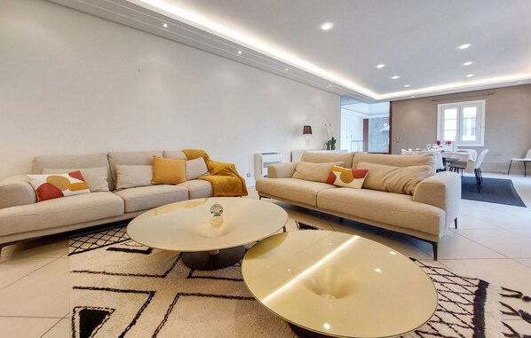 Ein modernes Wohnzimmer mit zwei Sofas, einem Couchtisch und einem Essbereich im Hintergrund.