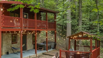 A cabin with a balcony, a hot tub, and a deck area.