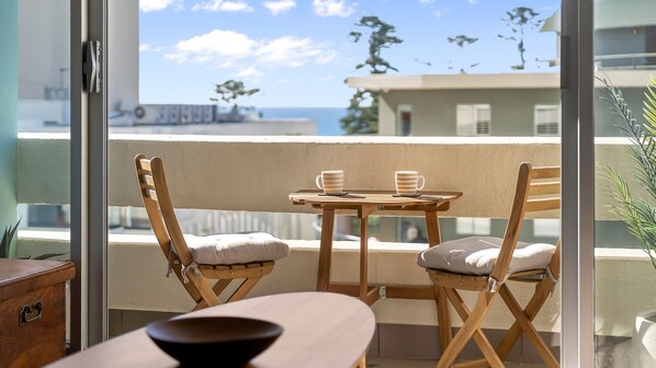A balcony with a table and chairs, a view of the sea, and a plant. - Water View Coastal Loft in Manly Pool Access (Manly)