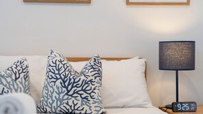 A bed with white and blue patterned pillows, a bedside lamp, and a digital clock displaying the time and temperature. - Water View Coastal Loft in Manly Pool Access (Manly)